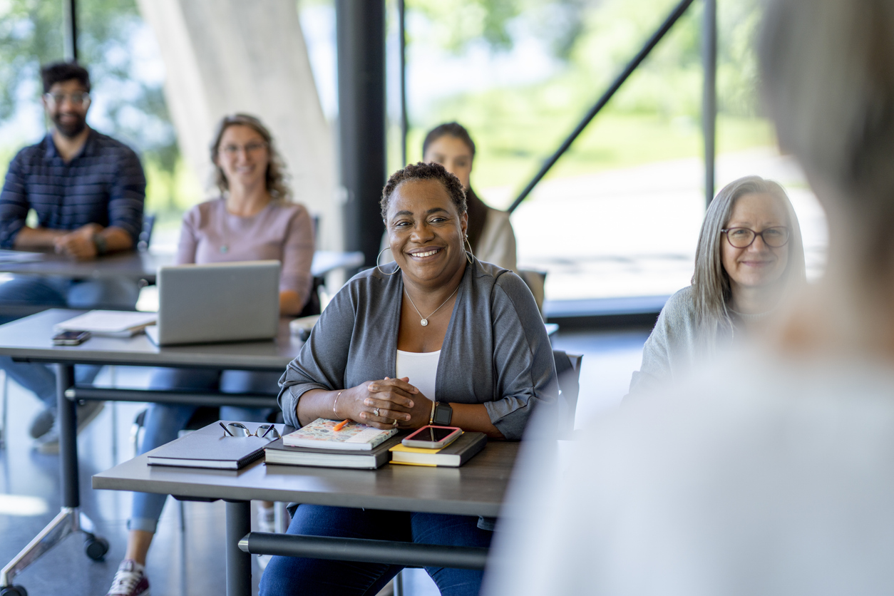 A class of adult students sit in class together as they listen attentively